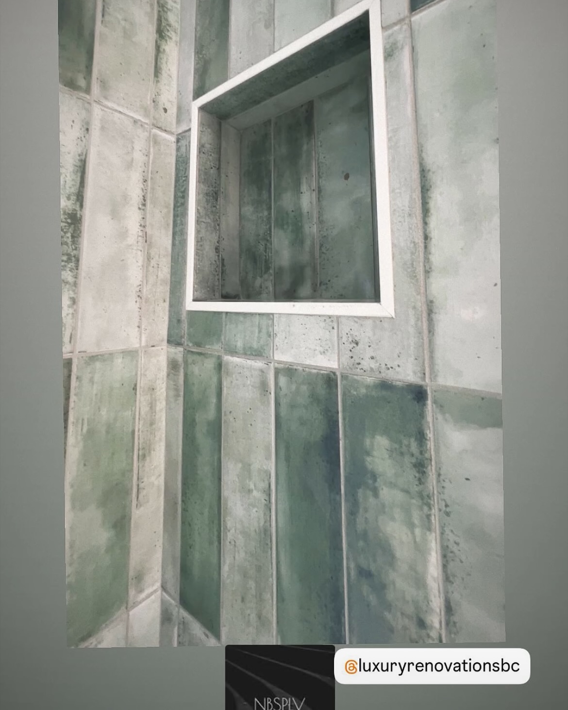 Elongated blue-green tiles surround a square recessed niche with a crisp metal border.