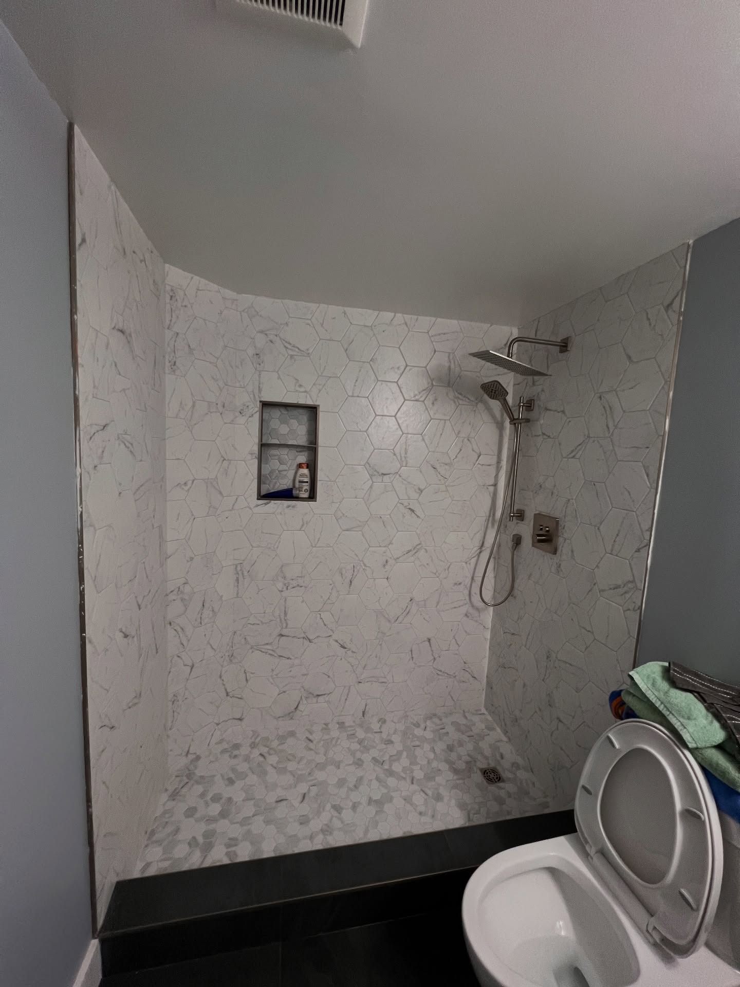 Large hexagonal wall tiles and a smaller hexagon mosaic floor bring two scales of pattern into this shower.