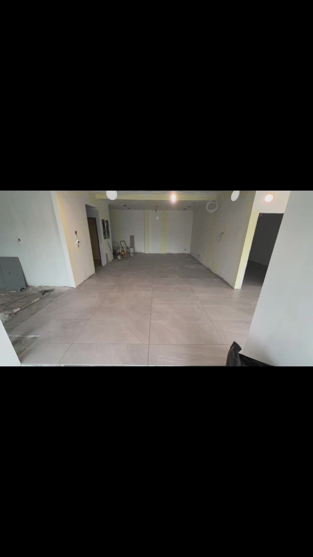 Large pale-grey floor tiles run through an open-plan interior with clean, regular grout lines.