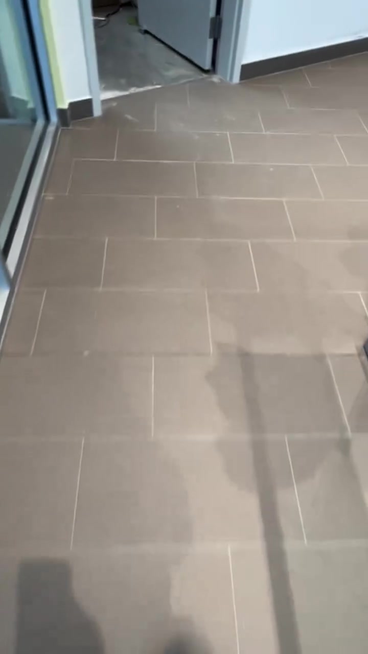 Warm grey rectangular floor tiles continue through a doorway in an offset layout.