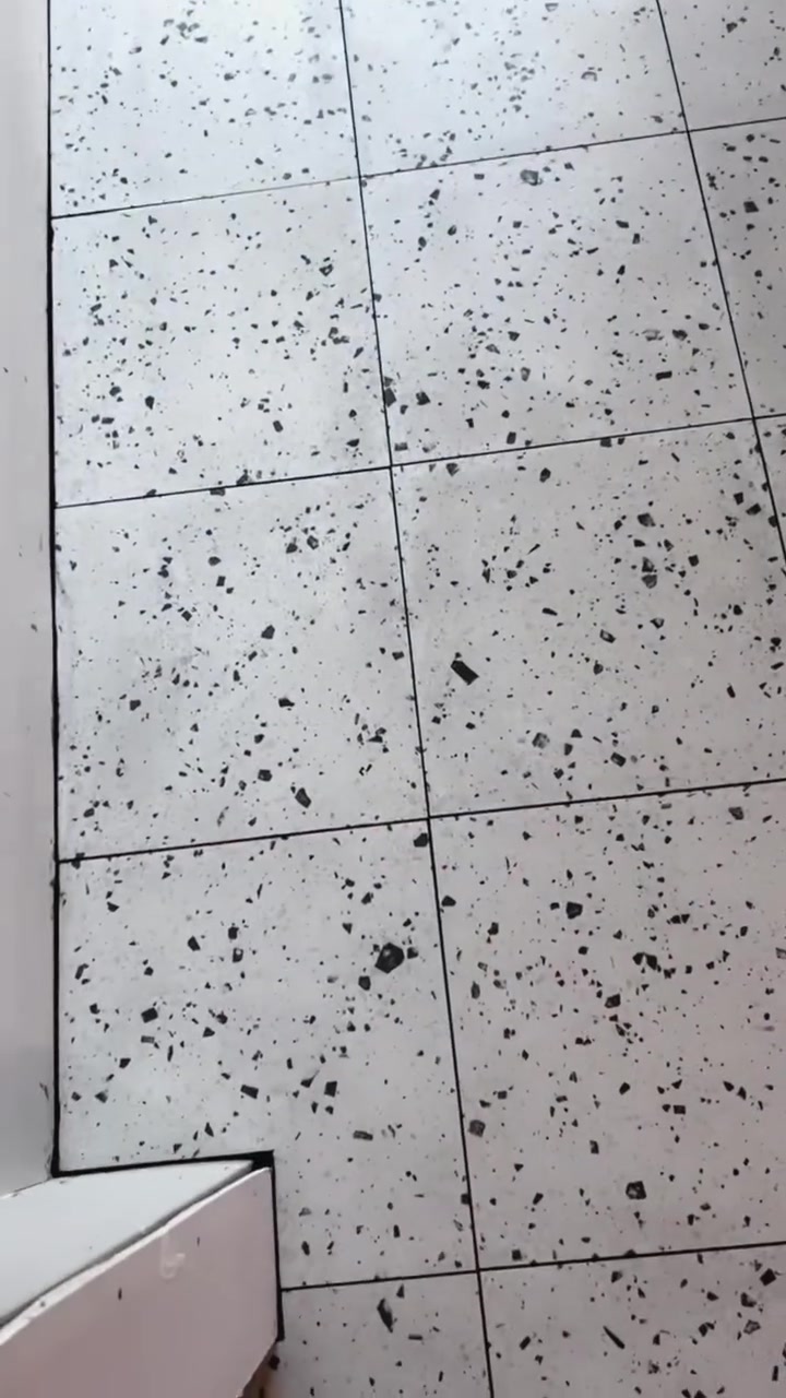Light, speckled floor tiles form a precise grid with a contrasting dark aggregate pattern.