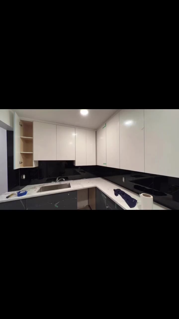 A dark backsplash runs around a corner kitchen beneath crisp white cabinetry.