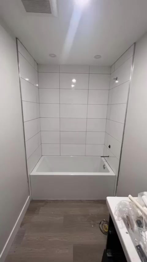 Large horizontal white tiles create a calm tub surround above a grey-toned bathroom floor.