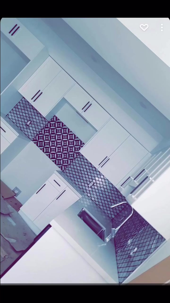 A bold geometric tile panel is framed by a smaller diamond-pattern backsplash beneath white cabinetry.